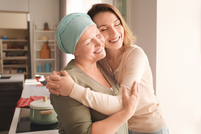 Mujer abrazando a otra mujer con cáncer hereditario.