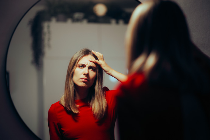 mujer mirando en espejo arrugas de la frente