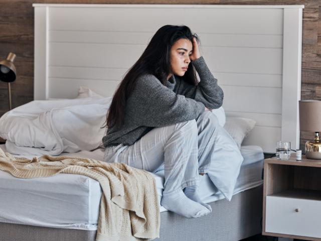 Mujer triste al lado de su cama