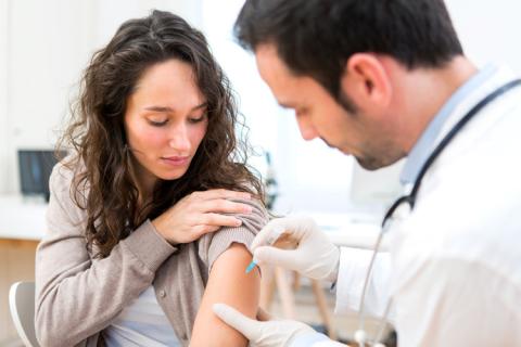 Médico poniendo una vacuna a una mujer joven