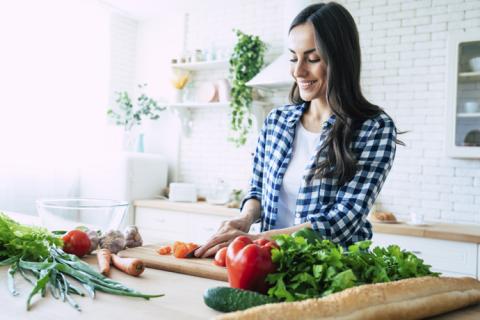Mujer prepara comida con alimentos anticancerígenos